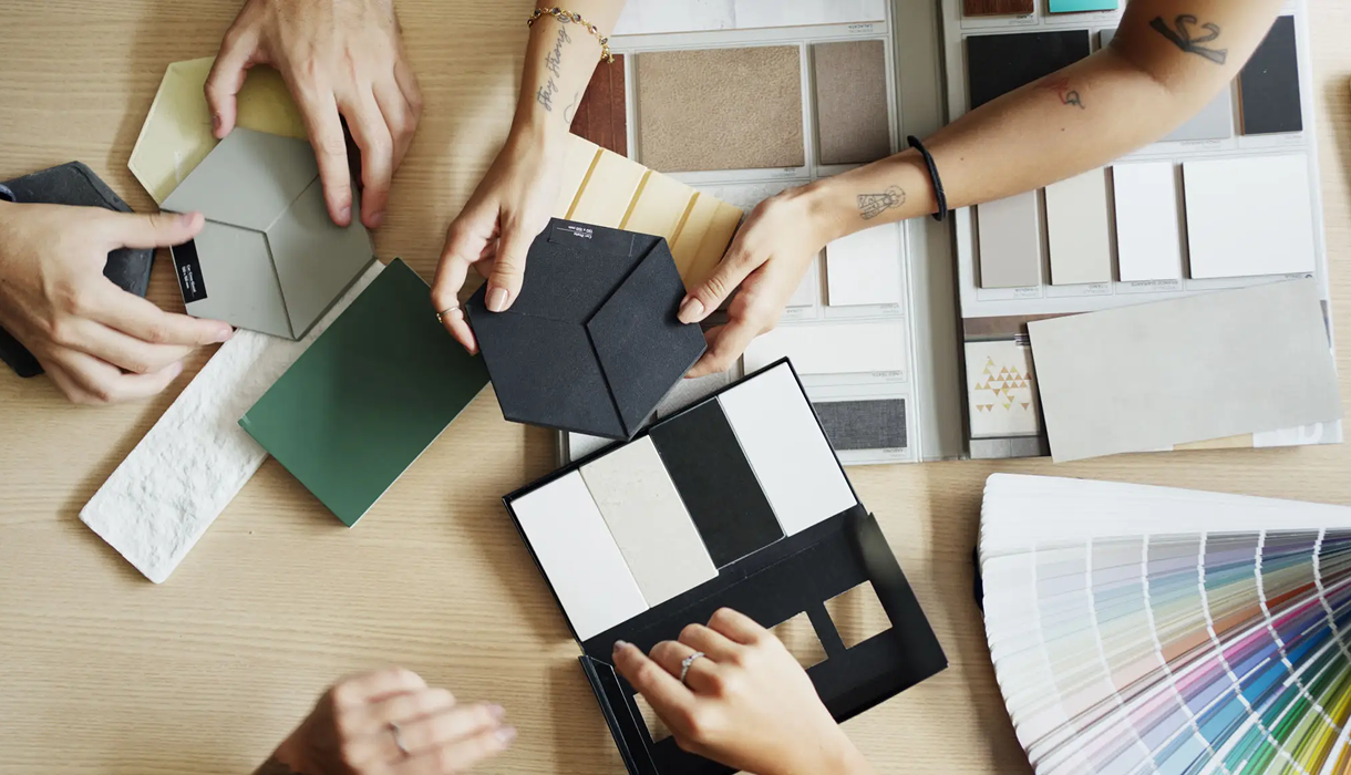 Overhead view of design process, swatches, and hands