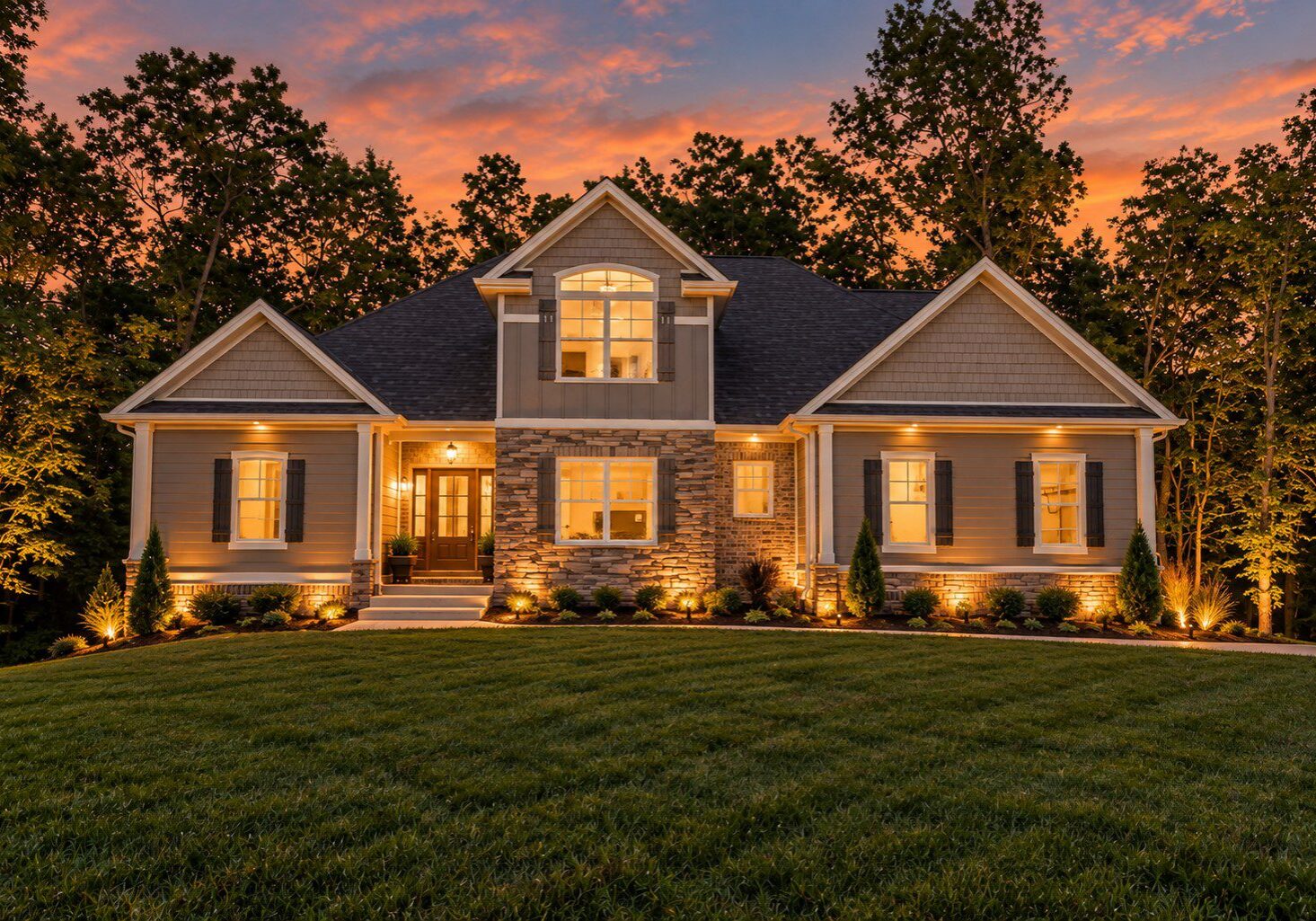 Beautiful house with illuminated landscaping at dusk